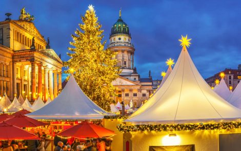 Festlicher Weihnachtsmarkt mit beleuchteten Zelten in der Abenddämmerung in Berlin.