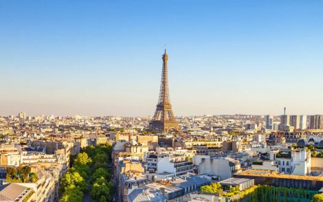 Paris Skyline mit dem Eiffelturm im goldenen Licht. Die Stadt erstreckt sich im Hintergrund unter blauem Himmel. Ideal für Busreisen oder Erlebnisreisen nach Frankreich.