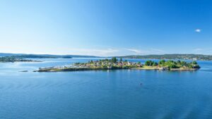 Idyllische Insel mit farbenfrohen Häusern und üppigem Grün unter strahlend blauem Himmel. Perfekt für Busreisen und Schiffsreisen, um unvergessliche Erlebnisreisen zu erleben.