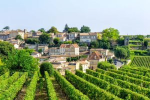 Panoramablick auf Saint-Émilion, Frankreich, mit Weinbergen im Vordergrund. Die mittelalterliche Stadt liegt auf einem Hügel mit typischen Steinhäusern und roten Ziegeldächern.