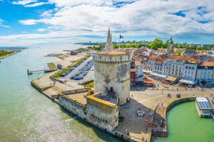 Historischer Turm Saint-Nicolas in La Rochelle, Frankreich, mit Blick auf den Hafen und die Stadt. Blauer Himmel mit Wolken im Hintergrund.