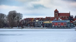 Winterliches Waren (Müritz) mit gefrorenem See und farbenfrohen Häusern am Ufer, im Hintergrund die Kirche.