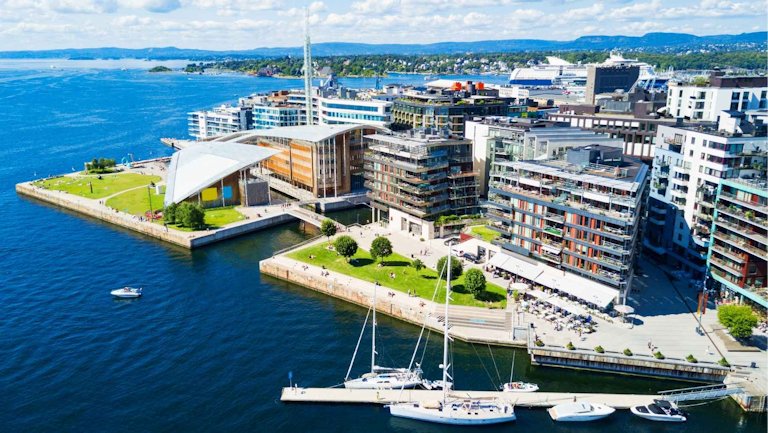 Oslo Fjord Panorama: Moderne Architektur am Wasser mit Segelbooten und Blick auf die Stadt. Sonniges Norwegen.