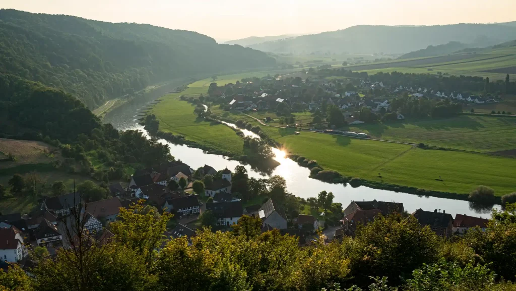 Weserbergland mit der Weser, Wiesen und bewaldeten Berghängen