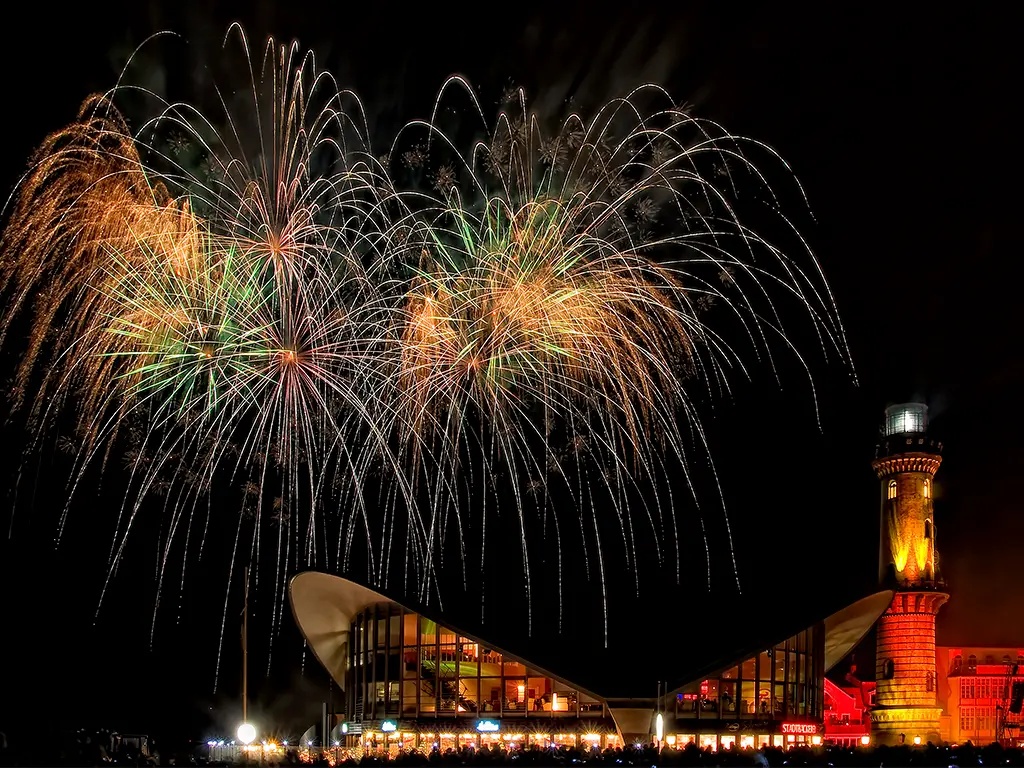 Feuerwerk in Warnemünde mit beleuchtetem Leuchtturm im Ostseebad.