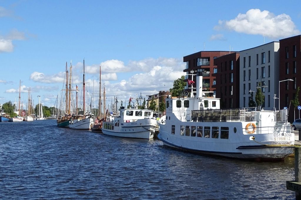 Sanddüne mit Blick auf die Ostsee auf Rügen. Gräser und Büsche im Vordergrund, blauer Himmel über dem Meer. Ideal für eine Ostsee-Auszeit.