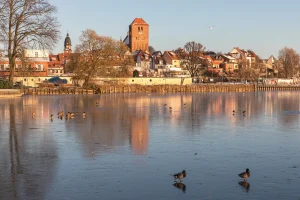 Waren an der zugefrorenen Müritz im Winter am Tag. Warmes Sonnenlicht strahlt auf die altstädtische Architektur.